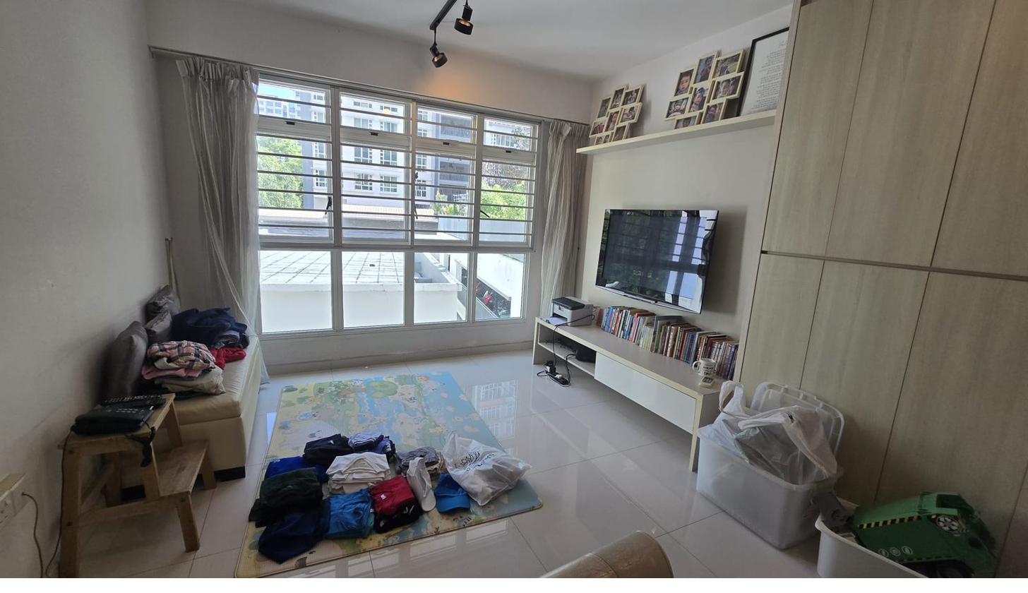 HDB living room before restyle — cluttered with toys, laundry on sofa